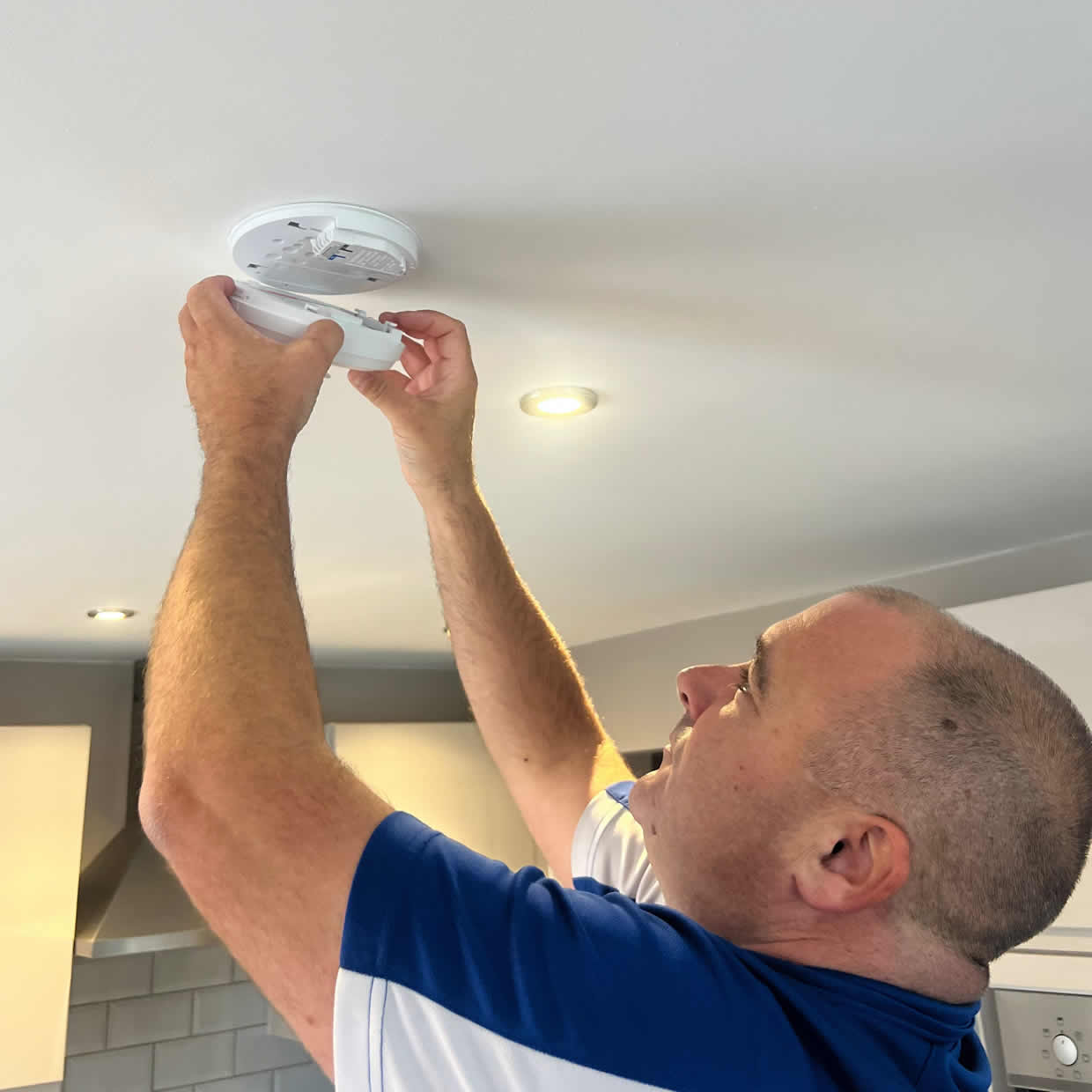 Smoke alarm installer fitting an alarm in a Redhill property